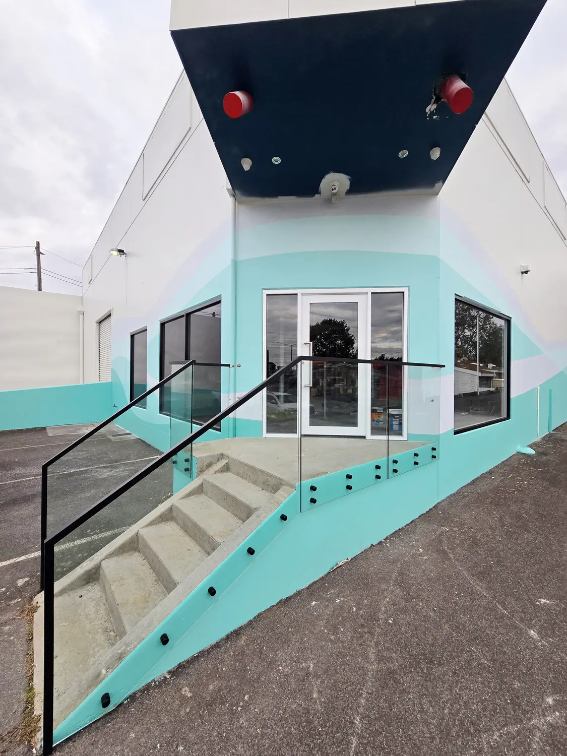 Glass balustrade with black posts running alongside external concrete stairs