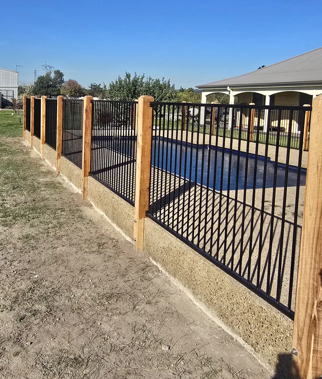 Aluminium pool fence with timber posts running along a property boundary