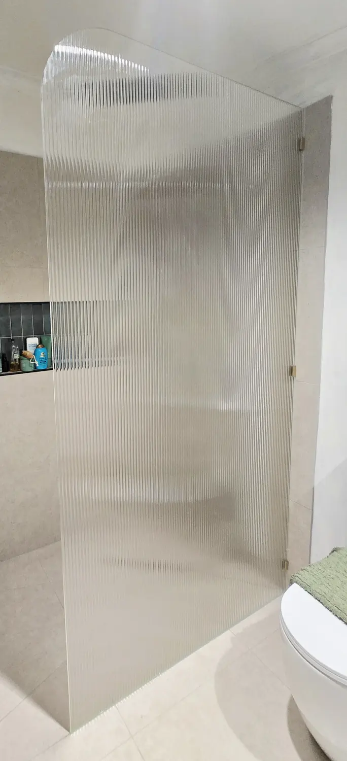 Fluted glass shower screen panel in a tiled bathroom