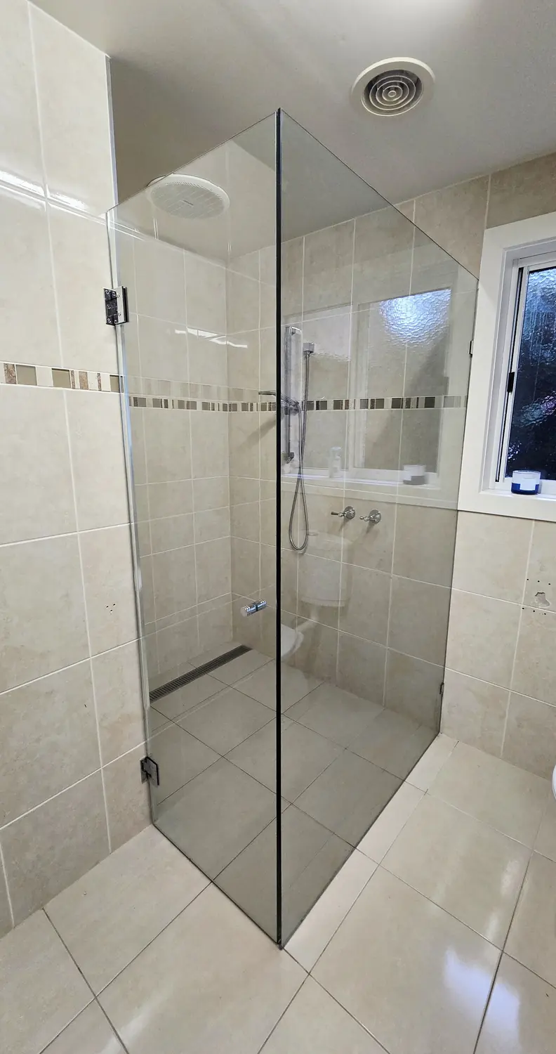 Framed shower screen and door in a tiled bathroom