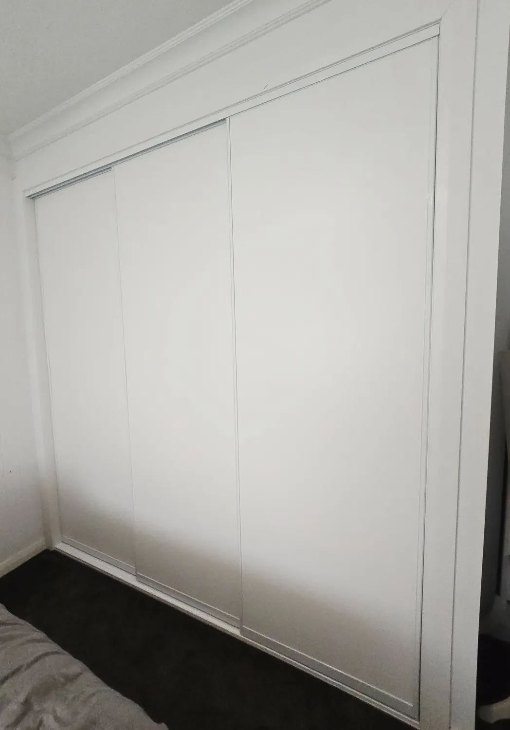 White sliding wardrobe doors fitted across a bedroom recess
